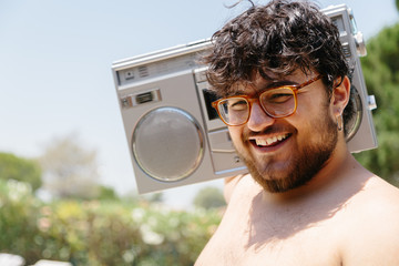 Young fat man with a pierced ear and glasses wearing a radio cassette on his shoulder