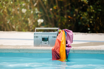 Metal radio cassette with an lgtb flag attached to the handle on a pool