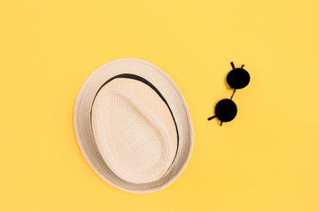 Straw hat and sunglasses on a yellow background. Bright summer layout.