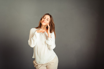 Young girl in a white shirt, hands up, on a gray background. Honest and emotional on the banner, billboard, billboard. No retouch. Without make-up.