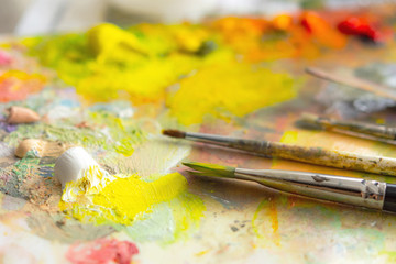 Oil paints on the artist's palette. Creative palette. Macrophotography of oil paints. Juicy summer shades on the palette. Art supplies. Artist's studio. Colors in selective focus.