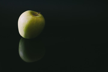 Single apple reflected on black background