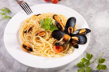 Popular italian pasta spaghetti with mussel from Taranto and tomatoes on a white plate with...