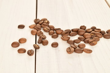 Fragrant roasted coffee grains, close-up, on a painted wooden table.