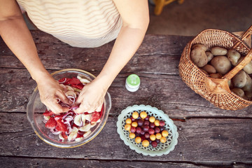 Woman preparing food and feast for summertime lunch at countryside rustic cottage outdoor kitchen.