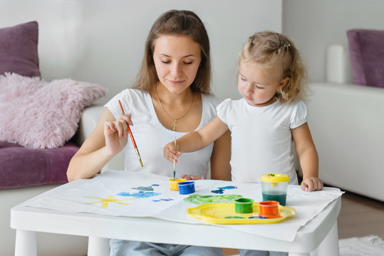 Mother and toddler child painting at home, creative family