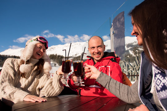 Group of happy friends cheering with drink after skiing day in cafe at ski resort.