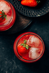two strawberry cocktail with ice on dark background