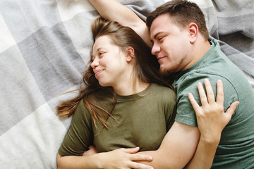 Portrait of affectionate embracing couple lying on a bed together, stay home concept, top view