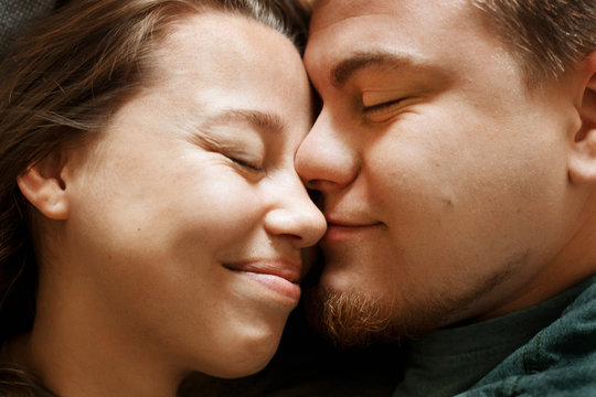 Emotional portrait of affectionate smiling kissing couple, close-up view