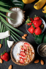  Smoothie bowl in coconut shell with strawberries, chia seed pudding, granola