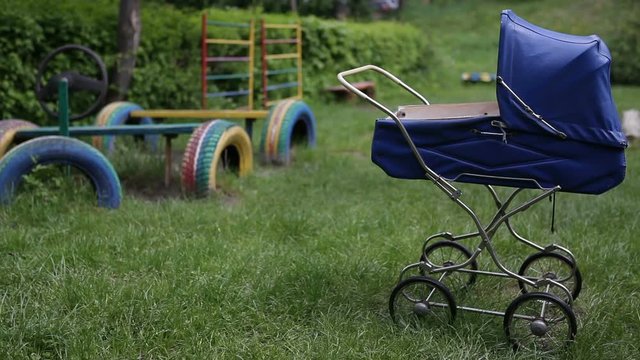 A baby stroller for a doll stands on the playground.