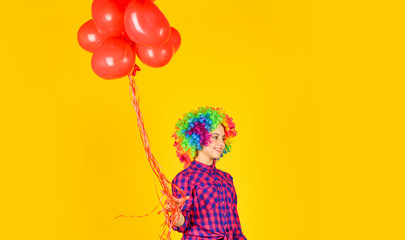 valentines day party. child wear rainbow wig hair yellow background. happy kid hold party balloons. heart balloons for love day. surprise for valentine. colorful and bright. small girl in periwig