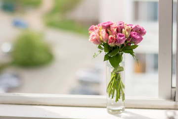 transparent vase with a bouquet of roses in a window 