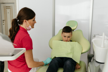 Stomatologist. Dental health. Female dentist curing a child patient in doctor's consulting room. Pediatric dentist.