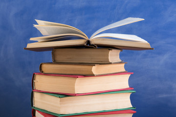 Education and reading concept - group of books on the wooden table, blue blackboard background. Teachers desk