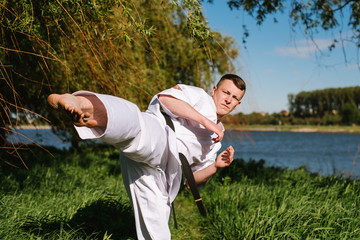 A man karate fighter in white kimono training outdoor in the park © rostyslav84