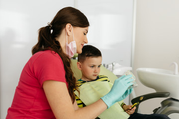 Dentist is teaching little boy about oral hygiene.