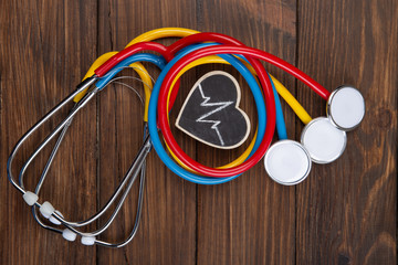 Workplace of a doctor. Colorful Stethoscopes and little heart on wooden desk background -...
