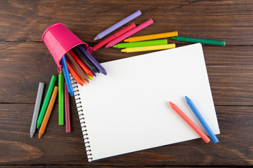 colored crayons and blank page on the wooden table
