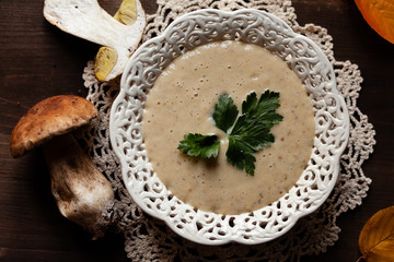 Delicious hot porcini puree soup, parsley. Tasty russian seasonal meal, perfect lunch. Fresh mashrooms as ingredients. Concept of homemade food. Closeup, dark wooden background flat lay top view
