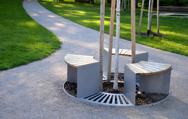 bench sitting round with wood paneling gray metal plate three seats around a tree around a gravel...