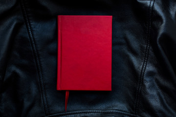 red notebook with bookmark on dark black leather texture background