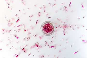A pile of pink petals in a small glass jar.