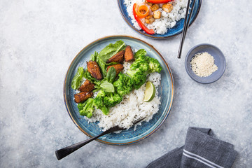 Vegan teryaki  tempeh or tempe buddha bowls  with rice, steamed broccoli, spinach  and lime on black  background. Healthy food