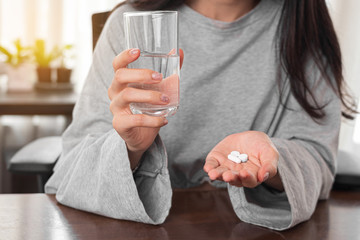 Close up woman taking pill and holding glass of water at home. woman taking medicine after doctor order.