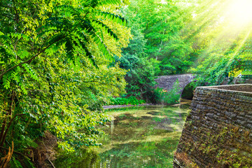 Sunset light pouring over stone arched footbridge and lazy river