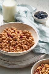 Dry granola in bowl. Breakfast, healthy diet food with milk in bottle, oat flakes