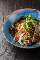 Asian vegetarian noodle soup, ramen with tofu, kimchi, vegetables and mushrooms in blue bowl. Slate background. Top view. Bowl of asian style soup. Japanese cuisine. Top view. Banner. Asian food