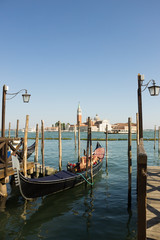 Fototapeta na wymiar Gondolas moored on the pier of Saint Mark square (Piazza San Marco), in the background is San Giorgio di Maggiore church, Venice, Italy