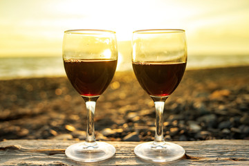 Two glasses of red wine at sunset on a background of the sea.