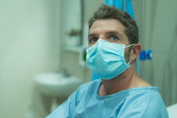 Fototapeta na wymiar attractive and scared man infected by covid-19 - dramatic portrait of adult male in face mask receiving treatment at hospital suffering respiratory disease sitting on bed worried