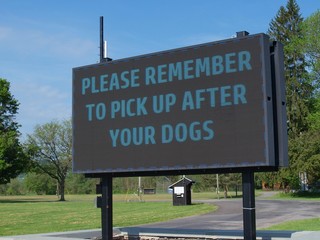 A municipal park sign reminds dog-walkers of the pooper-scooper law requiring them to pick up after...