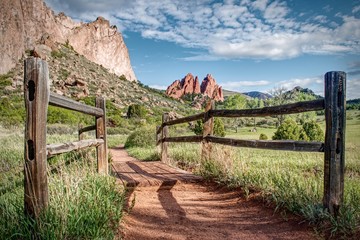 Wood fence frames a hiking trail which leads towards interesting rock formations in Garden of the Gods Park in Colorado Springs.
 - obrazy, fototapety, plakaty