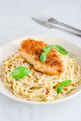 Spaghetti Pasta with Fried Chicken Garnished with Basil Leaves Directly Above Vertical Photo