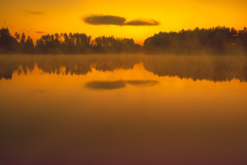 Magical sunrise over the lake. Serene lake in the early misty morning. Nature landscape