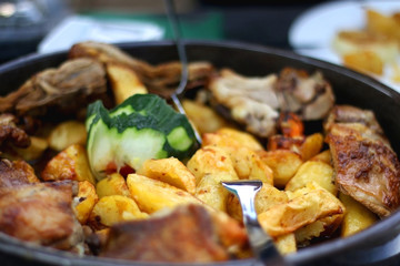 Traditional Croatian food - various meat and potatoes slow cooked under the iron bell ('peka'), served on a table. Selective focus.