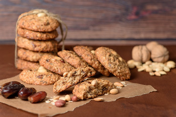homemade oatmeal cookies with dates, peanuts, coconut shavings on a wooden background, macro close-up. broken cookies in the foreground