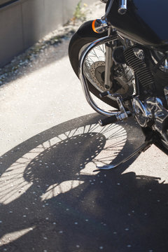 Fragment of a motorcycle with a shadow from the wheel in bright sunlight.