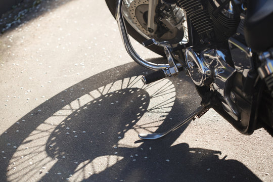 Fragment of a motorcycle with a shadow from the wheel in bright sunlight.
