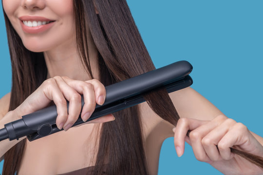 Close Up Picture Of A Woman Straightening Her Hair