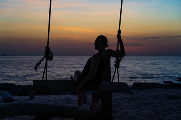 Girl swinging at sunset.