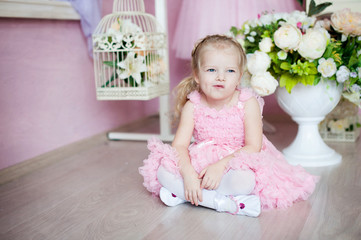 A little ballerina in a dress sits in a dance class on the floor. Legs crossed, mischievous face. Concept does not want to deal