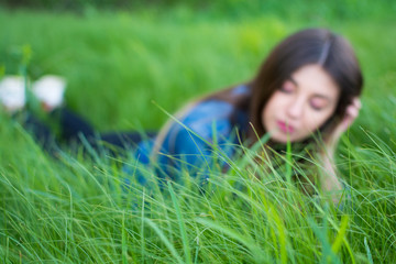 Girl with beautiful hair lying in the green, juicy grass. Warm spring evening
