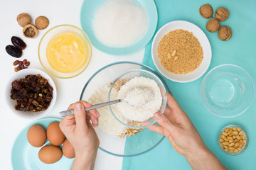 ingredients for the recipe homemade oatmeal cookies with dates, peanuts , coconut shavings, eggs, flour, salt in glazed plates on a light background. the view from the top