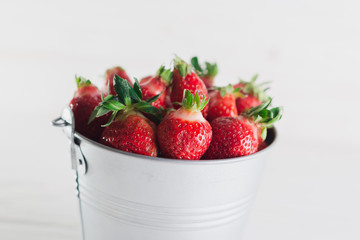 Juicy fresh strawberries in a metal bucket on a white background